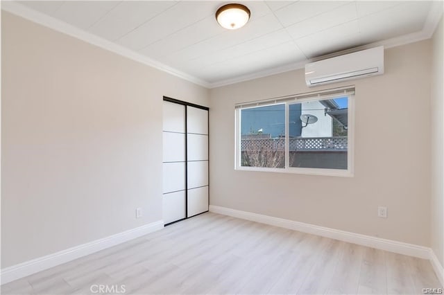 spare room featuring wood finished floors, crown molding, baseboards, and a wall mounted AC