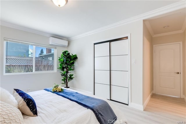 bedroom with baseboards, a wall unit AC, crown molding, light wood-style floors, and a closet