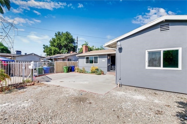 rear view of property featuring a patio, fence, and stucco siding