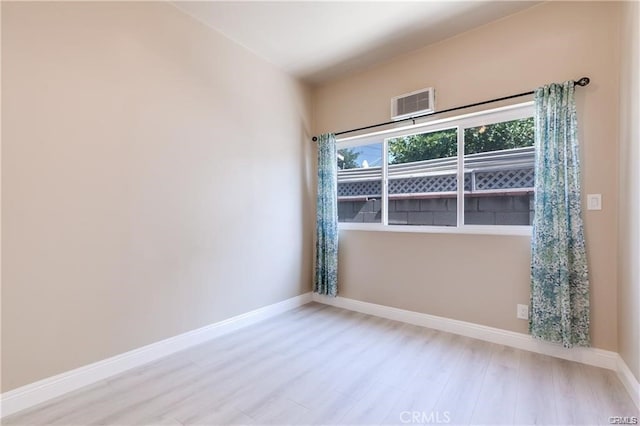 empty room with baseboards, visible vents, and wood finished floors