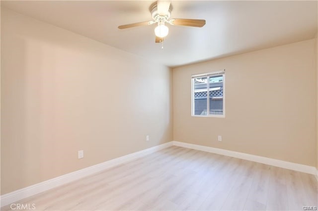 spare room with ceiling fan, light wood-style flooring, and baseboards