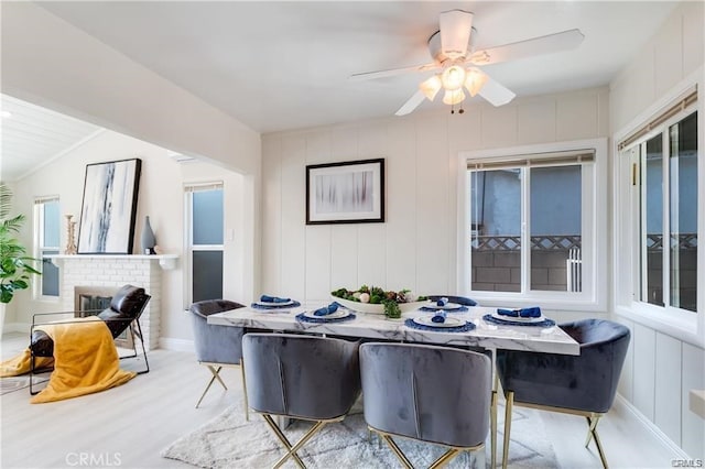 dining area featuring a wealth of natural light, a fireplace, a decorative wall, and wood finished floors