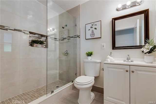 full bath featuring baseboards, toilet, tile patterned floors, a tile shower, and vanity