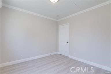 empty room featuring light wood finished floors, baseboards, and ornamental molding