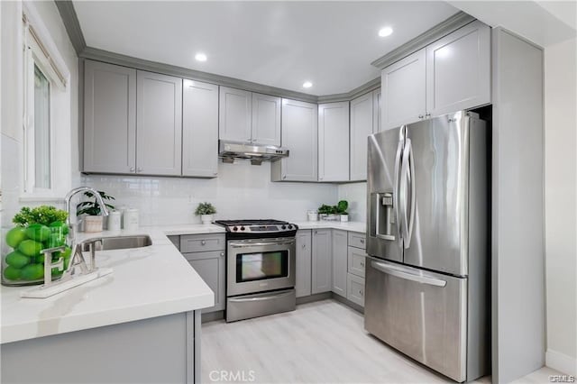 kitchen featuring backsplash, gray cabinets, stainless steel appliances, under cabinet range hood, and a sink