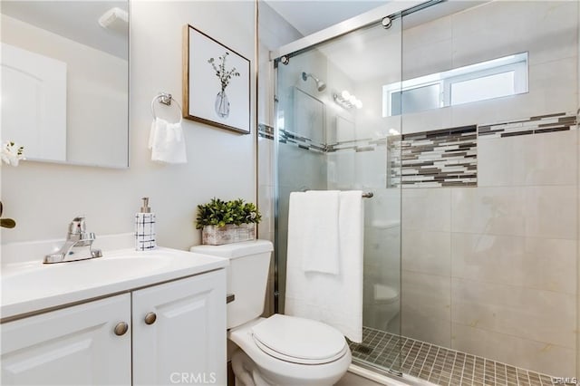 bathroom with vanity, a shower stall, and toilet