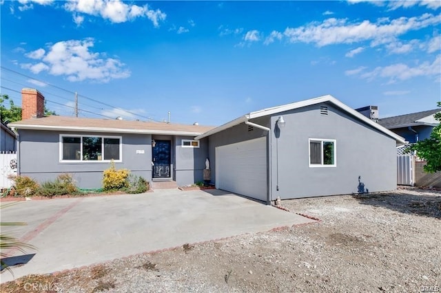 ranch-style house with a garage, concrete driveway, a chimney, and stucco siding