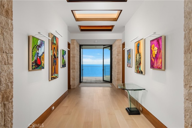 hall with expansive windows, a skylight, and wood finished floors