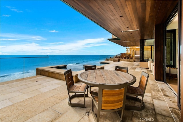 view of patio featuring a water view, a jacuzzi, and outdoor dining area