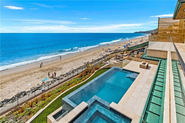 view of swimming pool with a water view and a beach view