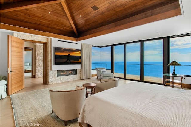 bedroom with a glass covered fireplace, lofted ceiling with beams, wooden ceiling, wood finished floors, and a wall of windows