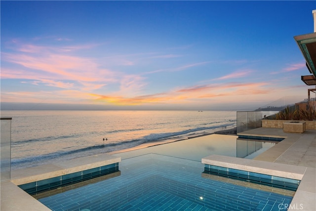 view of pool with a water view and a view of the beach