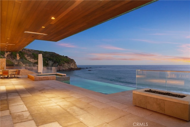 view of pool featuring a patio, a water view, and a pool with connected hot tub