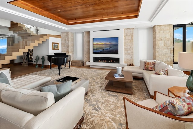 home theater room with a warm lit fireplace, a tray ceiling, and wood ceiling