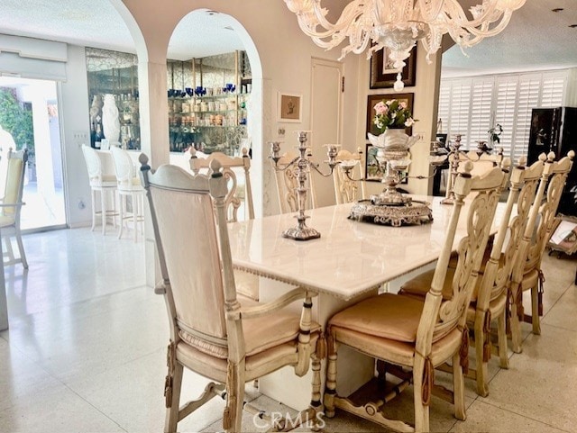 730 Santiago Ave, Long Beach, CA 90804 - dining room with arched walkways, a chandelier, healthy amount of natural light, and dark aggregate flooring