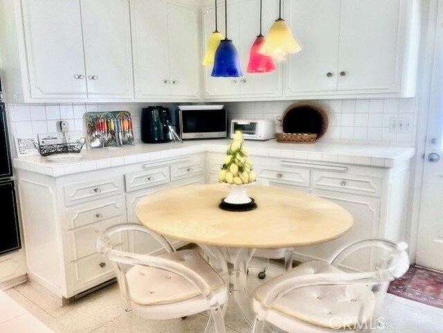 730 Santiago Ave, Long Beach, CA 90804 - kitchen with stainless steel microwave, tile countertops, and white cabinetry