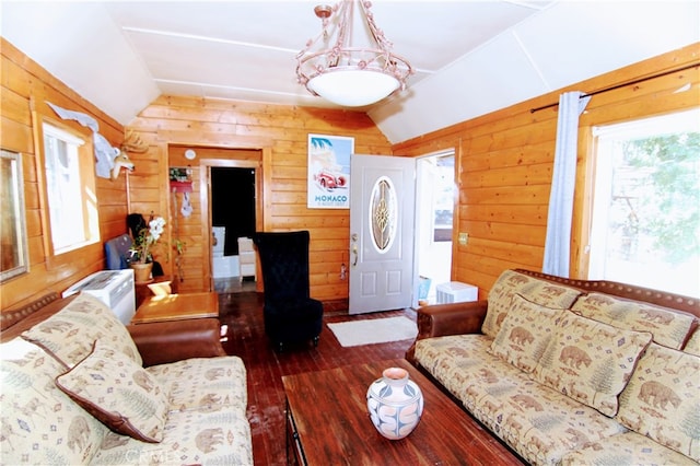 living area with a healthy amount of sunlight, wood walls, and vaulted ceiling