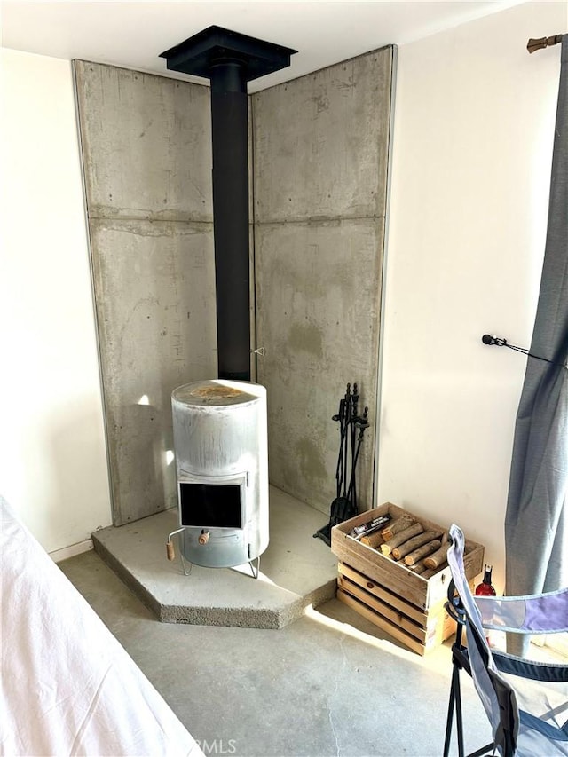 interior space featuring concrete floors, heating unit, and a wood stove