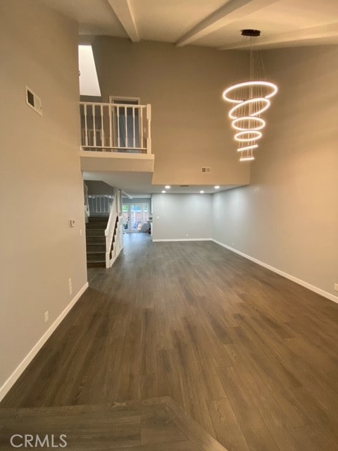 interior space with a chandelier, beam ceiling, and dark hardwood / wood-style flooring