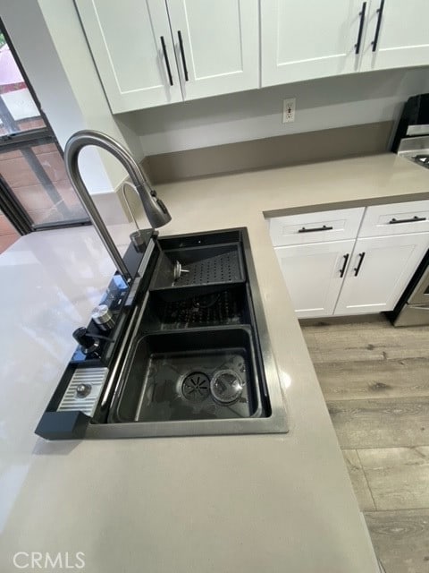 details with range, light hardwood / wood-style flooring, and white cabinets