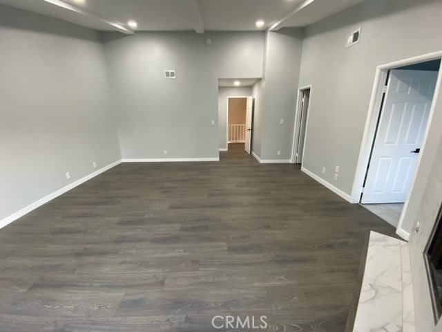 spare room featuring a towering ceiling and dark wood-type flooring