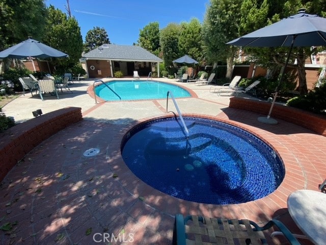 view of swimming pool with a community hot tub and a patio area