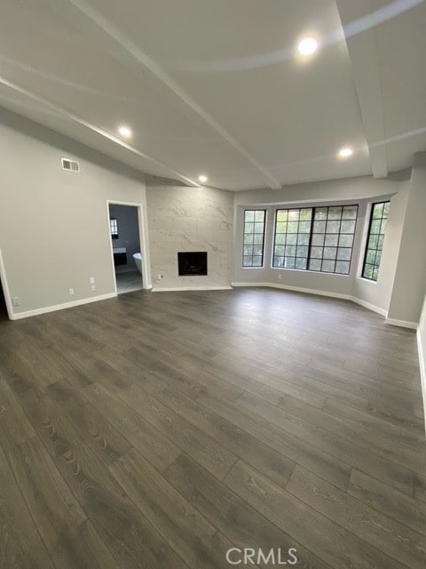 unfurnished living room with vaulted ceiling with beams, a high end fireplace, and dark hardwood / wood-style flooring