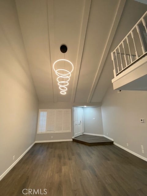 additional living space with dark wood-type flooring, vaulted ceiling, and a notable chandelier