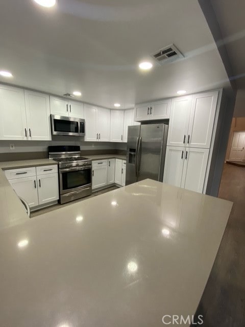 kitchen featuring dark hardwood / wood-style floors, white cabinets, and appliances with stainless steel finishes