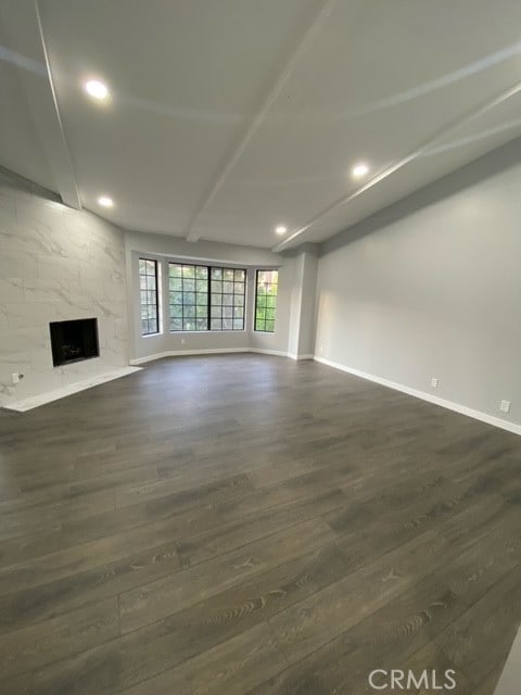 unfurnished living room with a high end fireplace and dark wood-type flooring