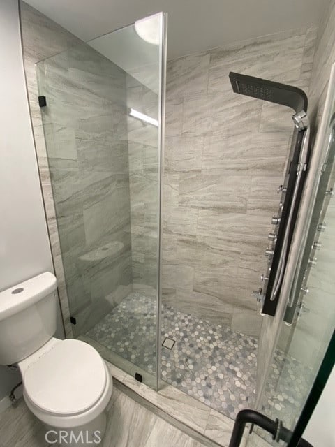 bathroom with a shower with shower door and toilet