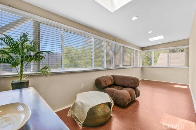 living area featuring recessed lighting, baseboards, wood finished floors, and a skylight