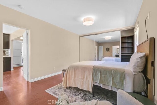 bedroom with wood finished floors, baseboards, and a closet