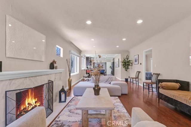 living room with a high end fireplace, recessed lighting, baseboards, and wood finished floors