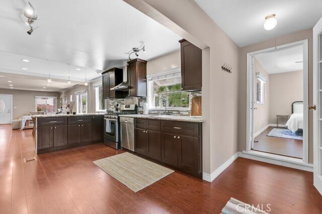 kitchen featuring dark brown cabinetry, appliances with stainless steel finishes, a peninsula, and a sink