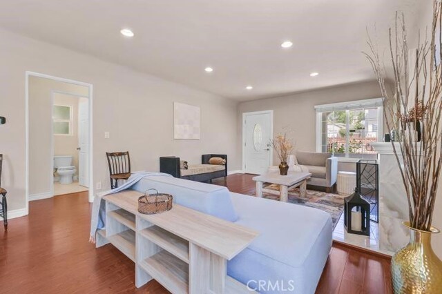 bedroom with recessed lighting, baseboards, ensuite bath, and wood finished floors