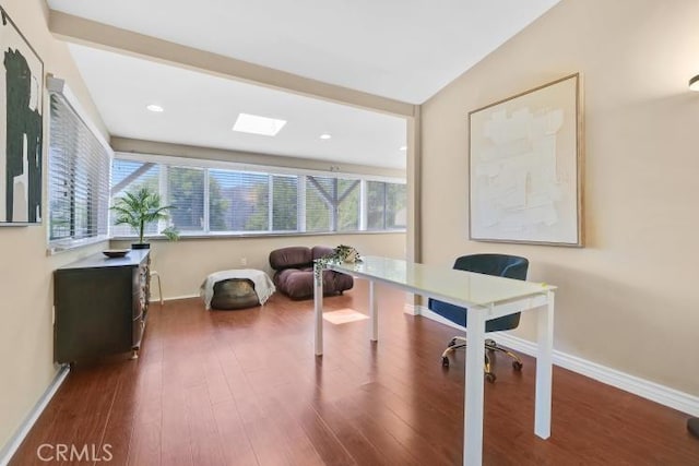 office featuring a skylight, baseboards, and wood finished floors