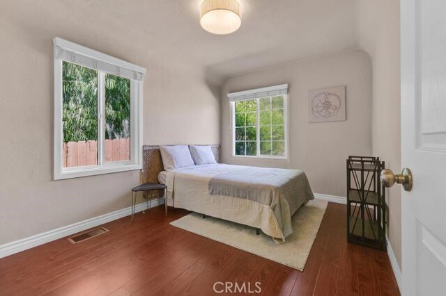 bedroom with visible vents, baseboards, and dark wood-style floors