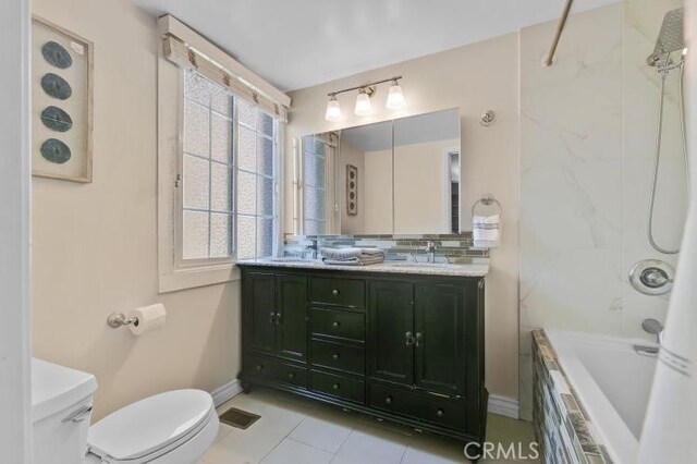 bathroom featuring a sink, tiled shower / bath, toilet, and double vanity