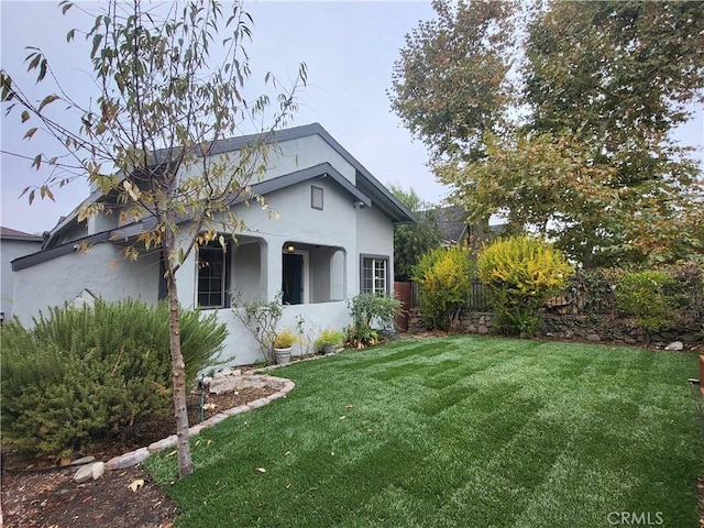 view of front facade featuring a front yard, fence, and stucco siding