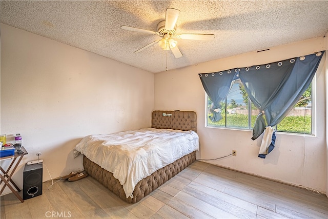 bedroom with wood-type flooring, ceiling fan, and a textured ceiling