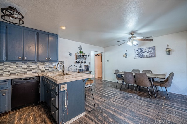 kitchen featuring black dishwasher, kitchen peninsula, tile counters, and dark wood-type flooring