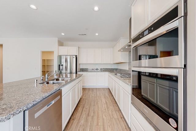 kitchen featuring sink, light hardwood / wood-style flooring, appliances with stainless steel finishes, light stone counters, and white cabinetry