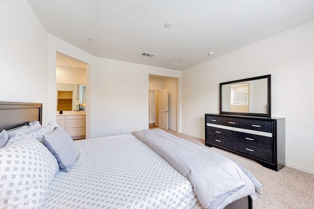 bedroom featuring ensuite bath and light colored carpet