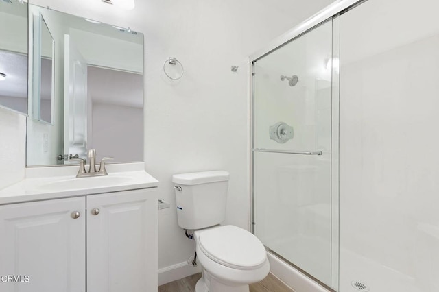 bathroom featuring toilet, a shower with door, and vanity