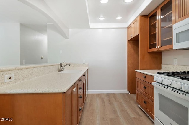 kitchen featuring light stone counters, sink, white appliances, and light hardwood / wood-style flooring