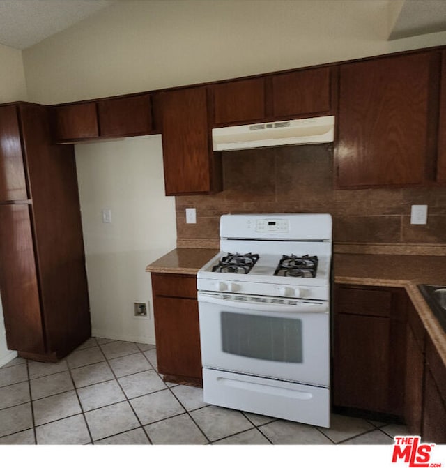 kitchen with dark brown cabinets, light tile patterned flooring, white range with gas stovetop, and tasteful backsplash