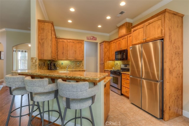 kitchen featuring a breakfast bar, light tile patterned flooring, kitchen peninsula, stainless steel appliances, and crown molding