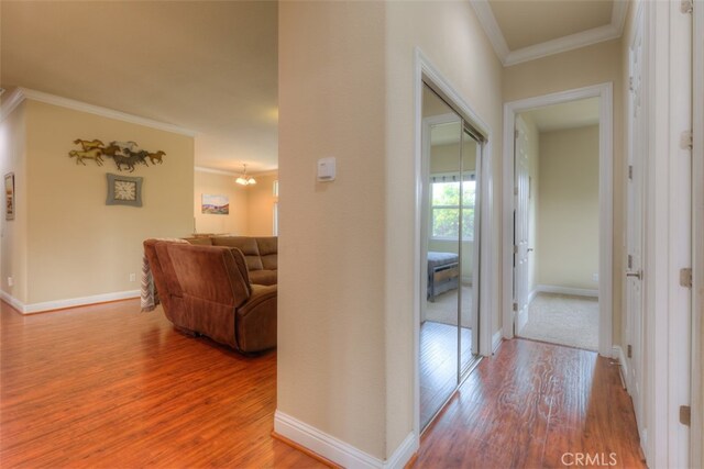 hall with a notable chandelier, ornamental molding, and hardwood / wood-style flooring