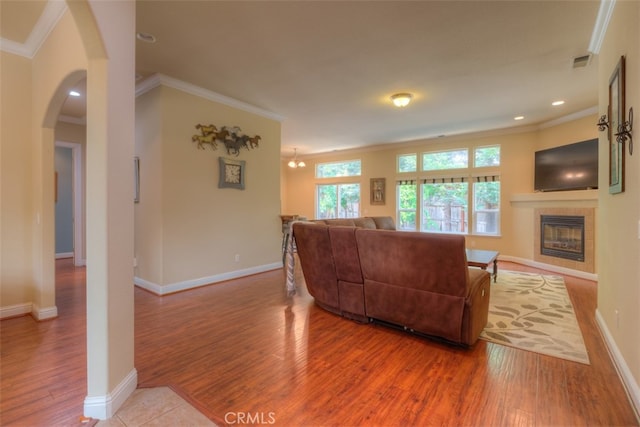 living room with hardwood / wood-style flooring, a fireplace, and ornamental molding